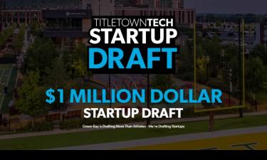 A promotional image for TitletownTech's Startup Draft, featuring large text that reads "$1 Million Dollar Startup Draft" over a background of a football field and surrounding campus. A subheading says, "Green Bay is drafting more than athletes – we're drafting startups."