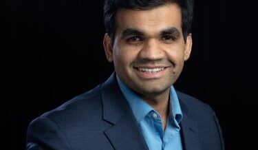 Professional portrait of man in suit in front of a solid black background  
