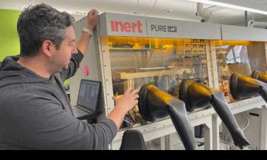 A man standing beside a fume hood. The image showcases a typical research and development setting, highlighting a chemical experimentation.