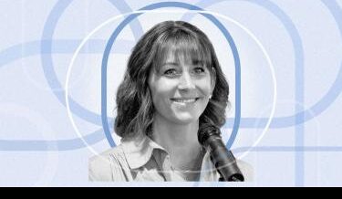 Black and white portrait of Megan O'Connor, smiling while speaking into a microphone. She has shoulder-length wavy hair and wears a light-colored blouse. The background is a light blue abstract pattern of interlocking circles.