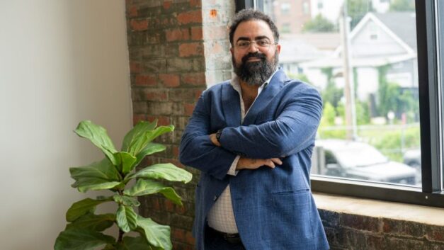 Hicham Ghossein stands with his arms crossed beside a window at his Knoxville office.