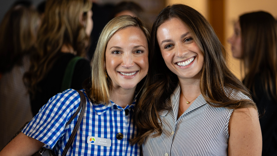 Two people, both with long hair, smile directly at the camera at LEEP Demo Day.
